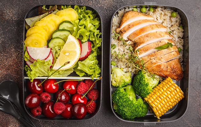 Healthy meal prep containers with grilled chicken with fruits, berries, rice and vegetables. Takeaway food jn dark background, top view
