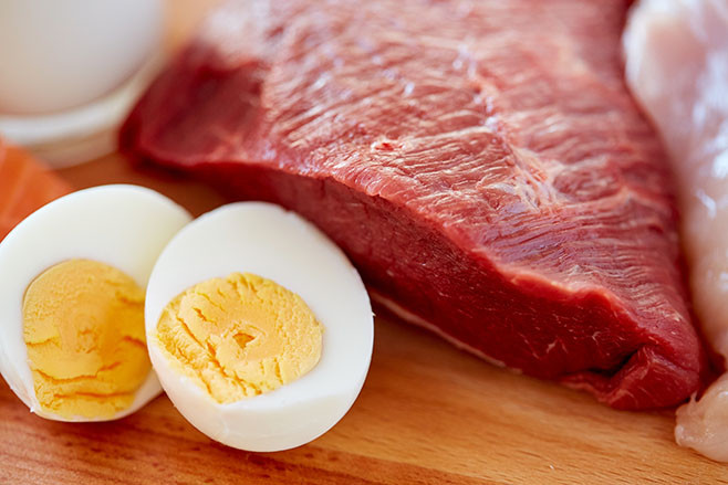 healthy lifestyle, culinary, cooking and diet concept - close up of red meat fillets and boiled eggs on wooden table