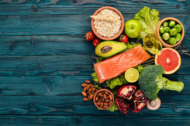 Healthy food. Fish salmon, avocado, broccoli, fresh vegetables, nuts and fruits. On a wooden background. Top view. Copy space.