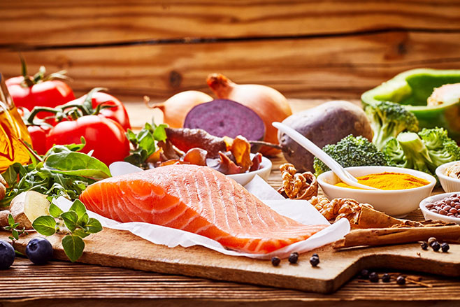 Healthy fresh raw food for the heart in a banner format on rustic wood with salmon, assorted spices, herbs, nuts, peppers, blueberries, tomato, onion, broccoli, garlic, soy sauce and olive oil