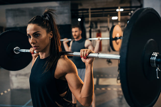 Young woman working out using a barbell at the gym