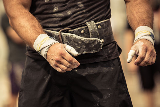 Closeup portrait of a bodybuilder girding on his bodybuilding belt