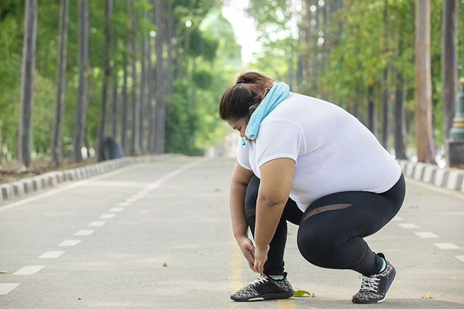 Picture of fat woman tying her shoelaces before doing jogging exercises on the road