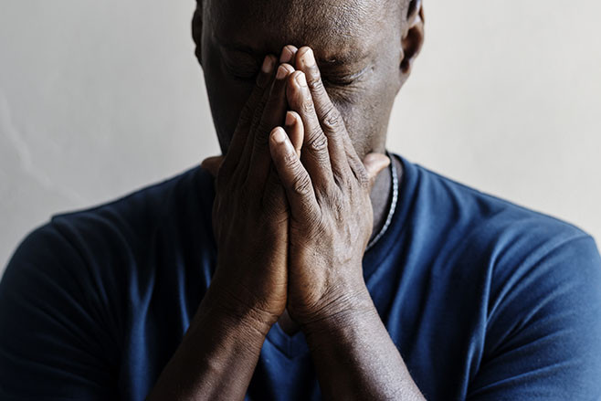 Black man with hands covered his face feeling worried