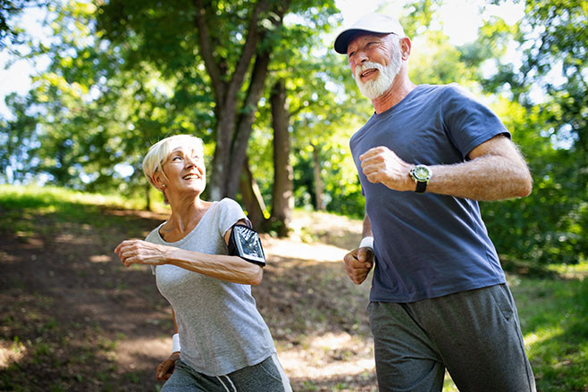 Mature or senior couple doing sport outdoors, running in a park