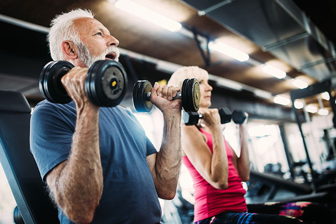 Happy mature people doing exercises in gym to stay fit