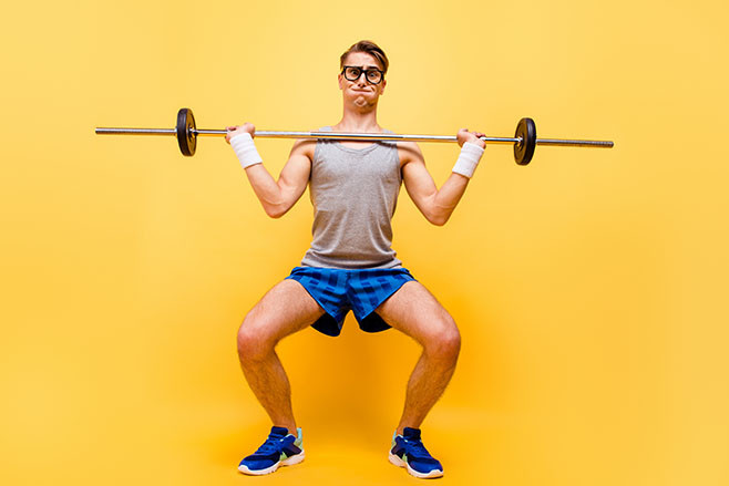 Full length body size of funky caucasian guy in glasses, doing physical exercises with dumbbell, isolated over bright vivid yellow background