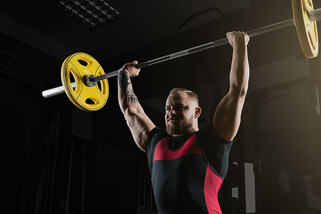 Professional powerlifter lifts the bar above his head in a squat. Rod push. Mixed media