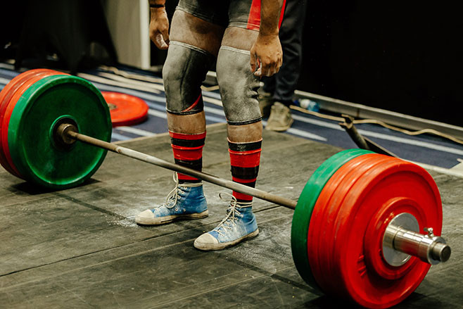 powerlifter legs in gym chalk and knee sleeves competition deadlift