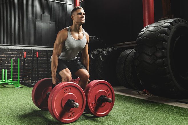 Young muscular sportsman doing farmer's walk exercise during his cross training workout