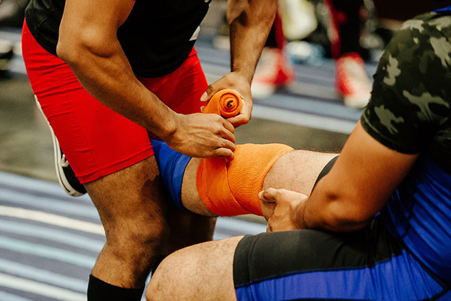 knee wraps with orange strap before squat with barbell